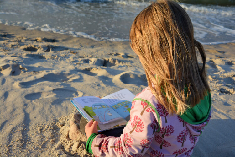 Kind liest am Strand