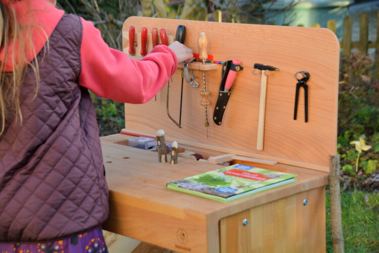Kind räumt Holz-Werkbank auf